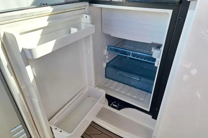 Slide: The Image of Open refrigerator inside 2014 Four Winns V375 boat, showing empty shelves and compartments. - 23