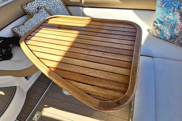 Slide: The Image of Wooden table on 2014 Four Winns V375 boat, surrounded by cushioned seating and decorative pillows. - 7