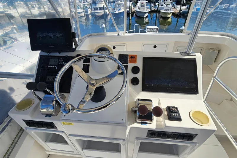 Slide: The Image of 2004 Luhrs 34 Convertible helm with steering wheel, navigation screens, and controls at marina. - 11
