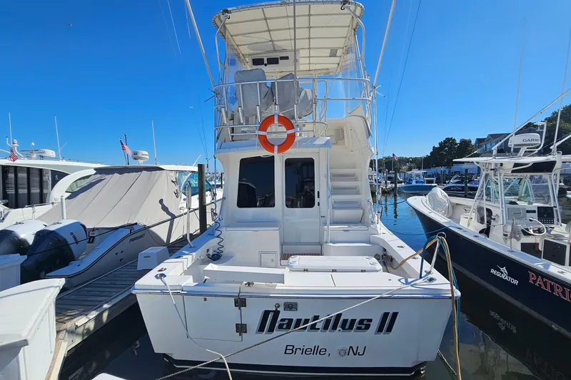 Slide: The Image of 2004 Luhrs 34 Convertible boat docked at marina, featuring upper deck and life preserver. - 2