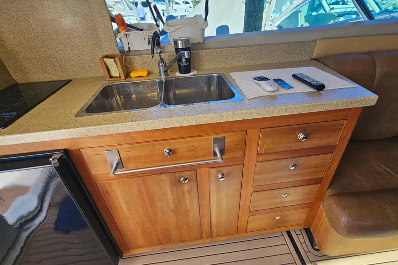 Slide: The Image of 2004 Luhrs 34 Convertible yacht kitchen with sink, wooden cabinets, and countertop accessories. - 31