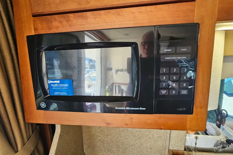 Slide: The Image of Microwave oven inside 2004 Luhrs 34 Convertible boat, featuring wood cabinetry and control panel. - 36