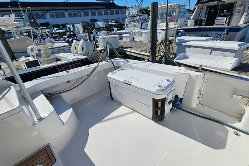 Slide: The Image of 2004 Luhrs 34 Convertible boat deck with cooler and docked vessels in marina. - 7