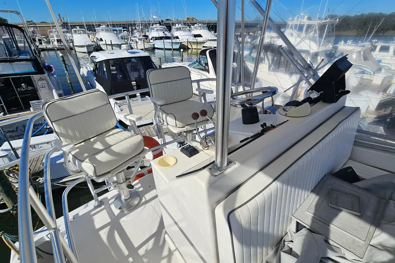 Slide: The Image of 2004 Luhrs 34 Convertible boat interior with helm chairs and marina view. - 9