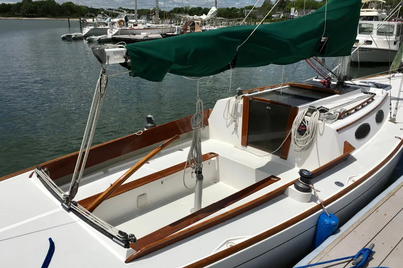 Slide: The Image of 1995 Alerion Express 28 sailboat docked, featuring a green sail cover and wooden trim. - 3