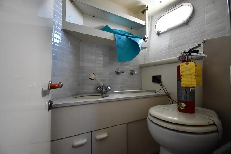 Slide: The Image of Bathroom interior of 2001 Ferretti Yachts 72, featuring sink, toilet, and fire extinguisher. - 113