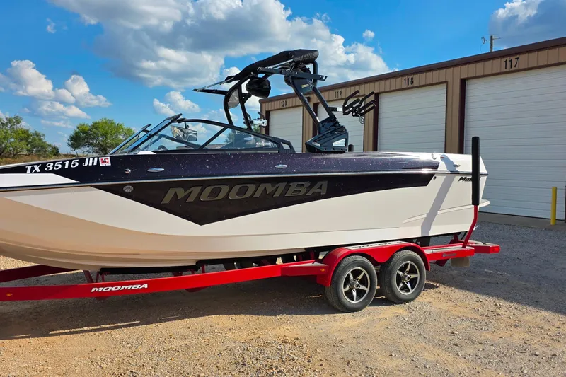 Slide: The Image of 2020 Moomba Makai boat on red trailer, parked near storage units under a blue sky. - 1