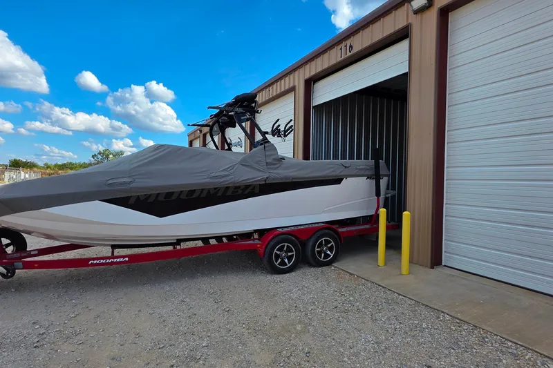 Slide: The Image of 2020 Moomba Makai boat on trailer, covered, near storage unit under blue sky. - 31
