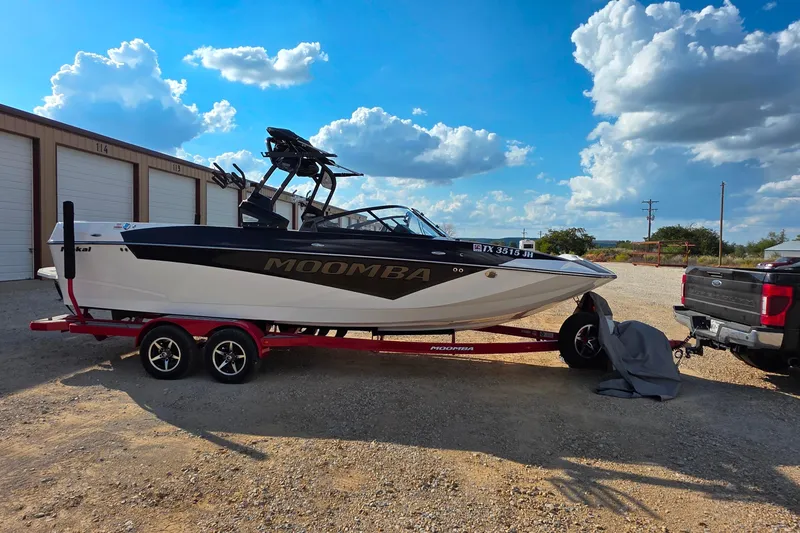 Slide: The Image of 2020 Moomba Makai boat on red trailer, parked outdoors under a blue sky. - 6