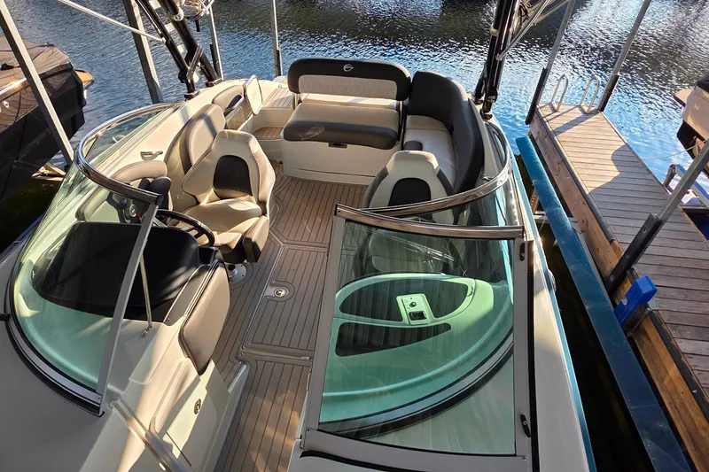 Slide: The Image of 2022 Crownline 255 SS SURF boat interior with seating and steering wheel, docked by water. - 23