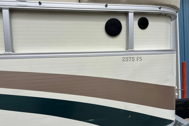 Slide: The Image of 2006 Bennington 2575 FS boat side view with beige and green stripes. - 10