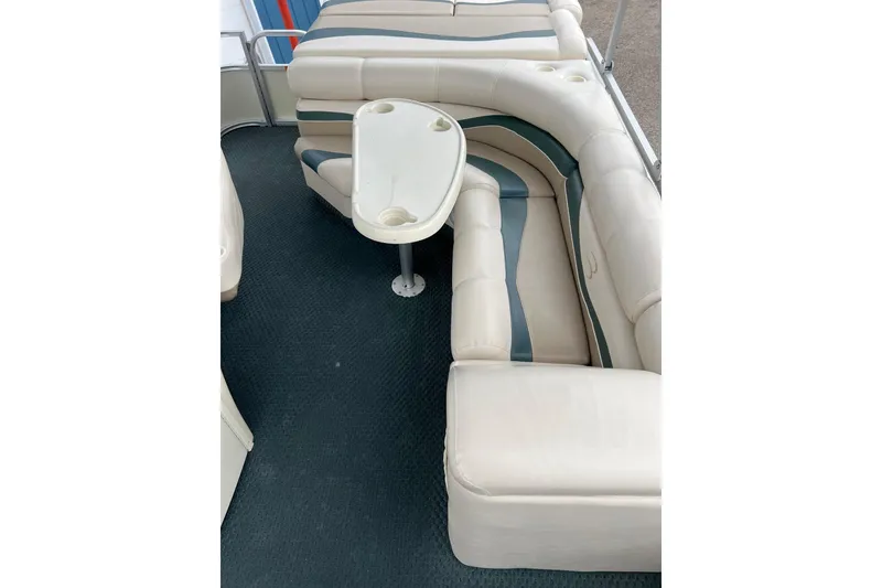 Slide: The Image of 2006 Bennington 2575 FS boat interior with beige seating and a small table. - 24