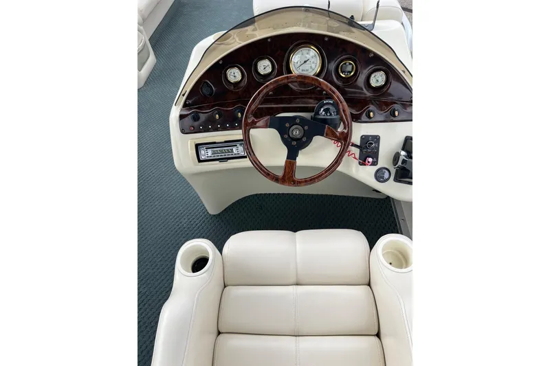 Slide: The Image of 2006 Bennington 2575 FS boat dashboard with wood accents and beige seating. - 26