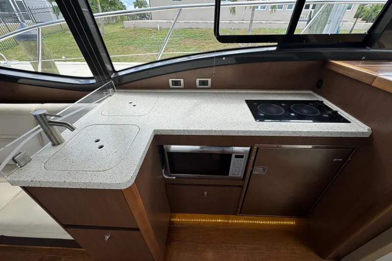 Slide: The Image of Modern kitchen area in 2016 Sea Ray 400 Sundancer yacht with stove, sink, and microwave. - 18