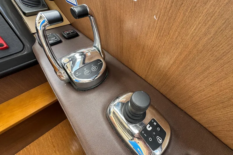 Slide: The Image of 2016 Sea Ray 400 Sundancer throttle and joystick controls on wooden panel. - 25