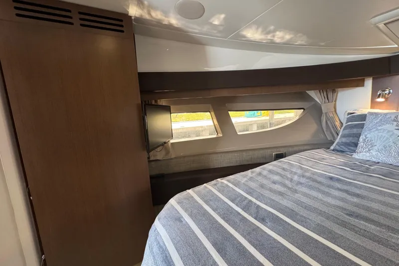 Slide: The Image of Luxurious cabin interior of 2016 Sea Ray 400 Sundancer with striped bedding and window view. - 30