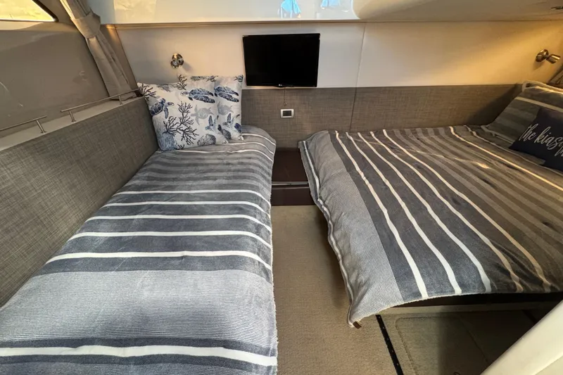 Slide: The Image of Interior of 2016 Sea Ray 400 Sundancer with striped bedding and decorative pillows. - 35