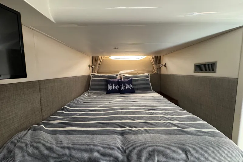 Slide: The Image of Interior cabin of 2016 Sea Ray 400 Sundancer with striped bedding and decorative pillows. - 38