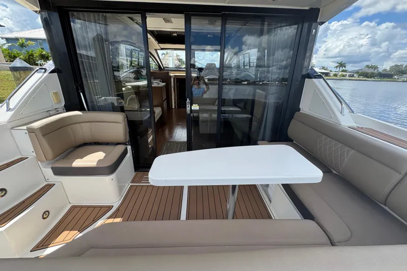 Slide: The Image of 2016 Sea Ray 400 Sundancer yacht with elegant outdoor seating and table, docked by the water. - 7