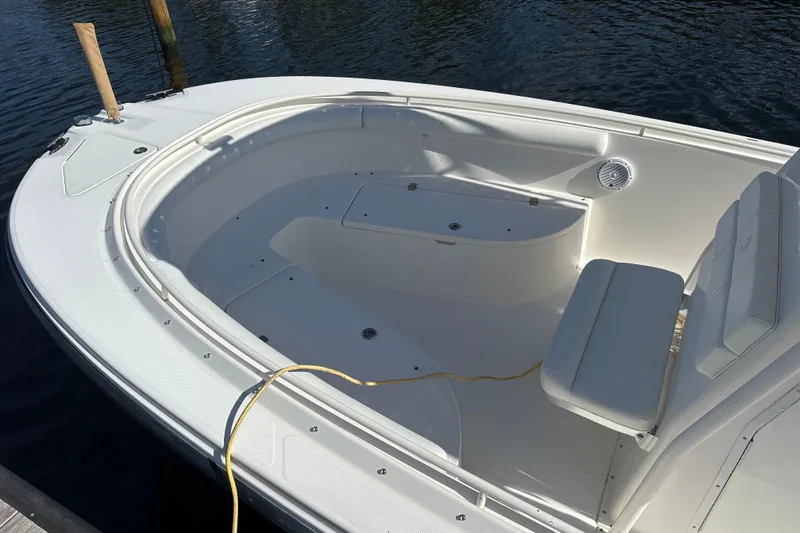 Slide: The Image of 2004 Edgewater 245CC boat interior with seating and storage, docked on calm water. - 10