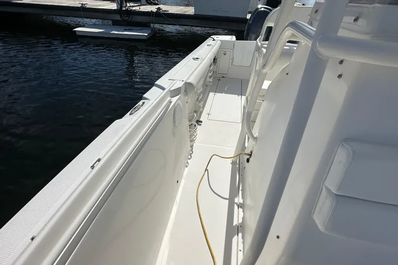 Slide: The Image of 2004 Edgewater 245CC boat interior, featuring white deck and seating, docked by the water. - 15