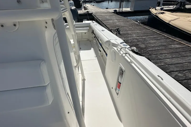 Slide: The Image of 2004 Edgewater 245CC boat docked, featuring a clean white deck and safety equipment. - 16