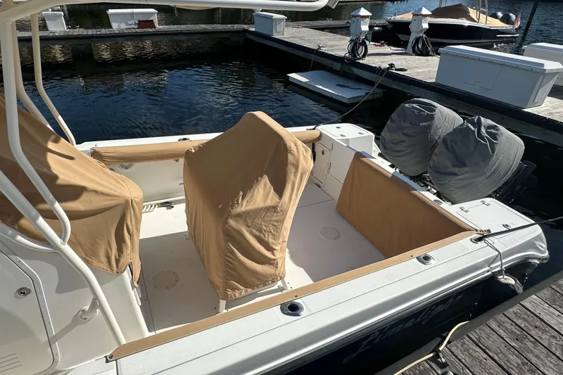 Slide: The Image of 2004 Edgewater 245CC boat docked, featuring covered seats and dual outboard motors. - 25