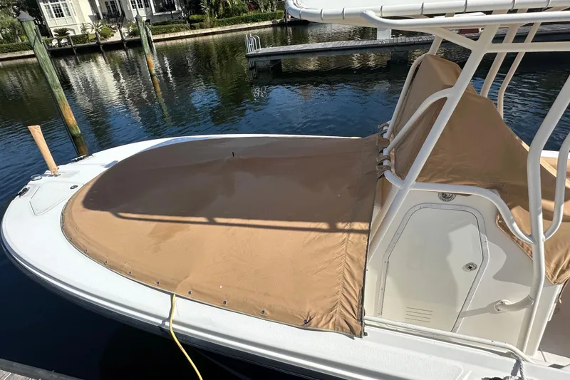 Slide: The Image of 2004 Edgewater 245CC boat with tan cover docked by the water. - 26