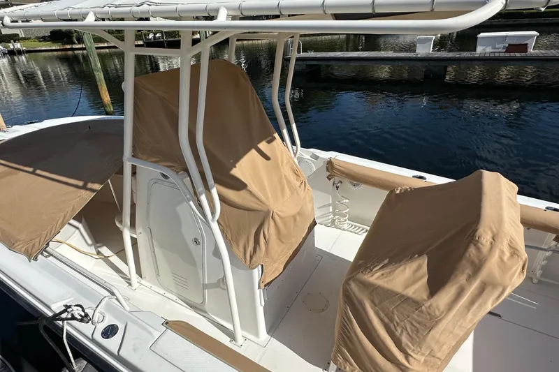 Slide: The Image of 2004 Edgewater 245CC boat with tan covers docked by the water. - 27