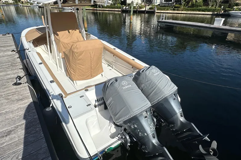 Slide: The Image of 2004 Edgewater 245CC boat docked with twin Yamaha engines, covered seats, and calm water backdrop. - 28