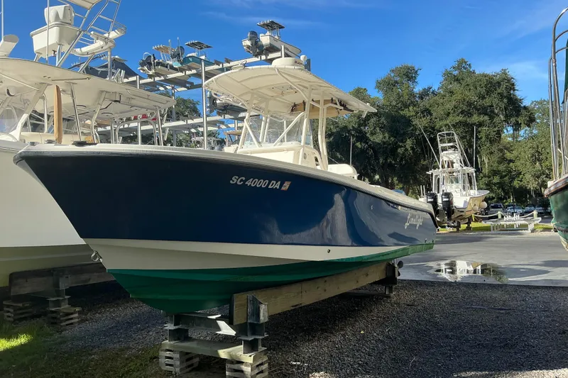 Slide: The Image of 2004 Edgewater 245CC boat on display in a marina, surrounded by trees and other boats. - 6