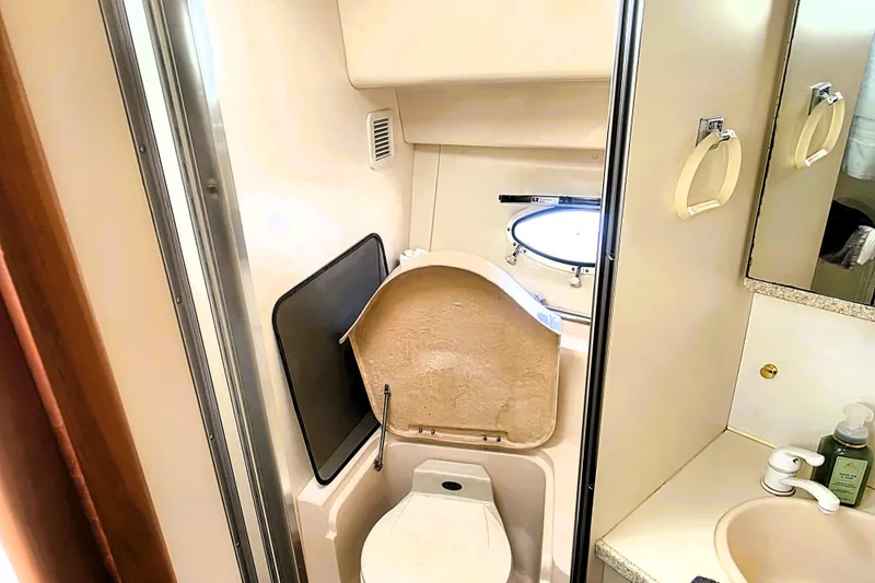 Slide: The Image of 1998 Silverton 352 Motor Yacht bathroom with toilet, sink, and porthole window. - 13