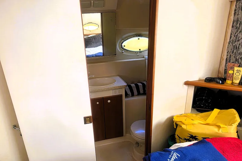 Slide: The Image of 1998 Silverton 352 Motor Yacht bathroom with sink, mirror, and porthole window. - 16