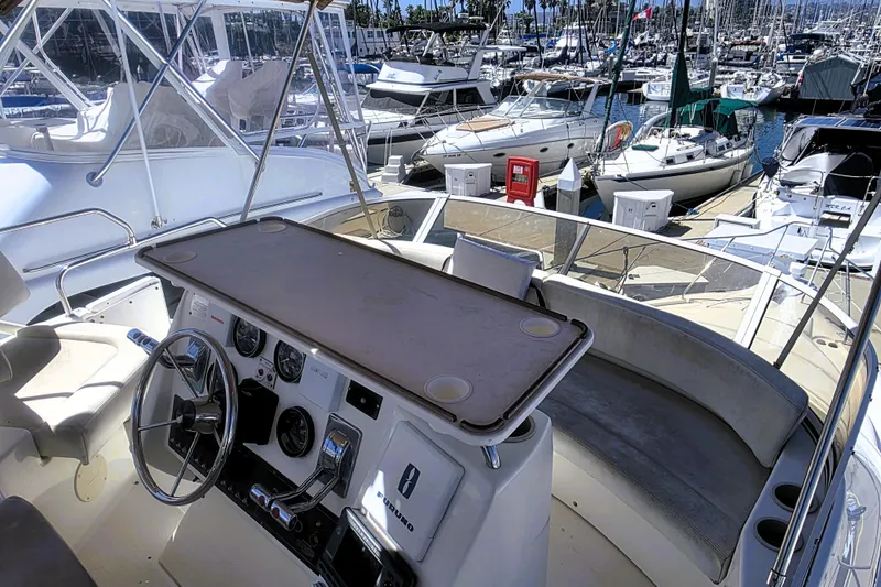 Slide: The Image of 1998 Silverton 352 Motor Yacht helm with marina view, featuring steering wheel and control panel. - 21