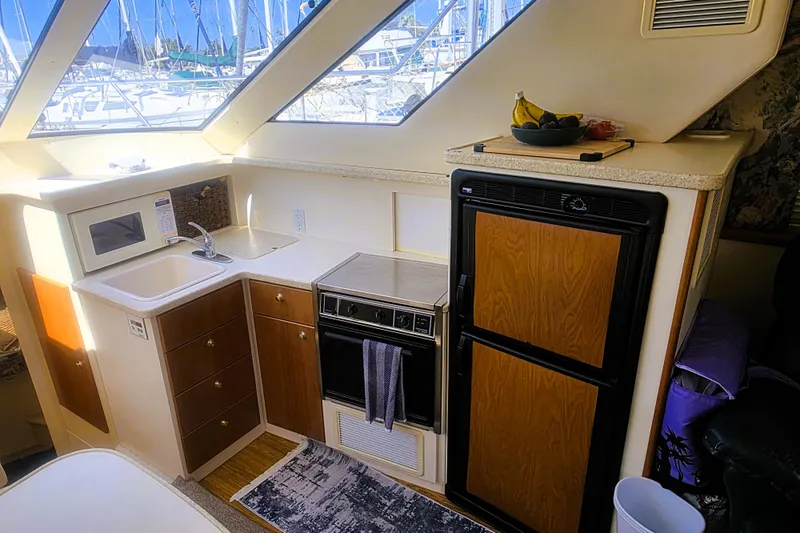 Slide: The Image of 1998 Silverton 352 Motor Yacht kitchen with sink, microwave, stove, and refrigerator. - 9