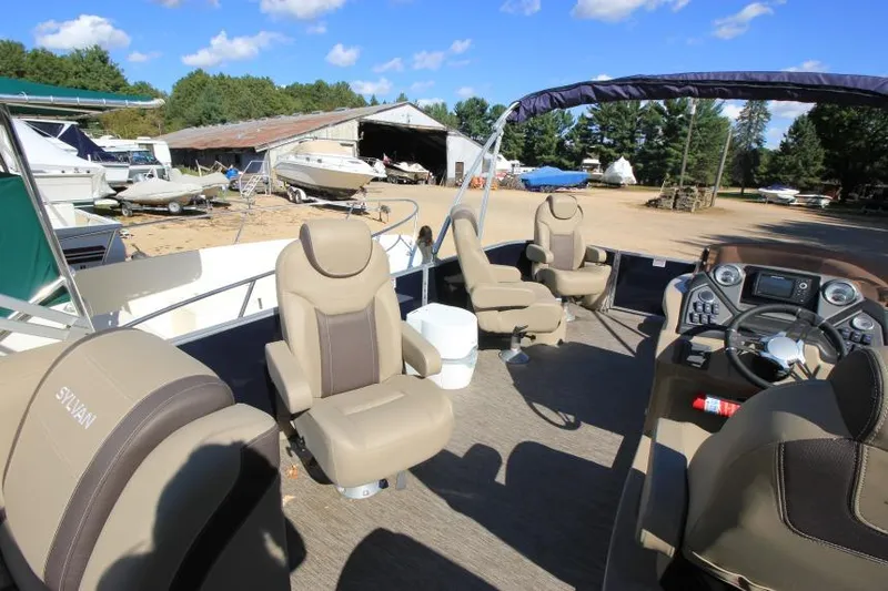 Slide: The Image of 2022 Sylvan L3 LZ pontoon boat interior with beige seating and steering console. - 14