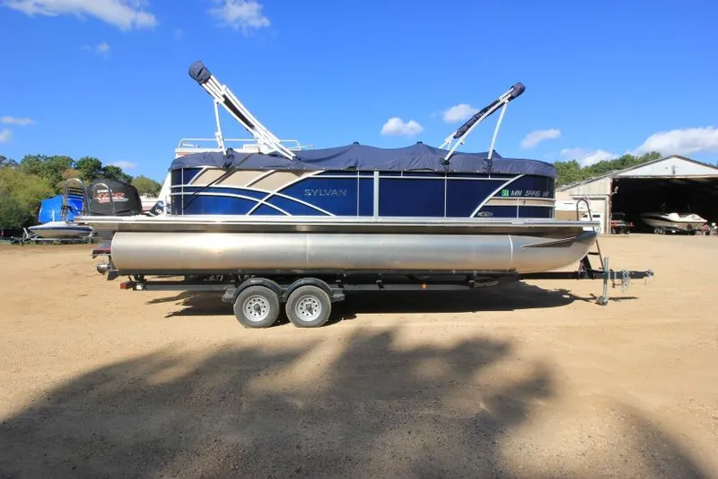 Slide: The Image of 2022 Sylvan L3 LZ pontoon boat on trailer, parked outdoors under blue sky. - 2
