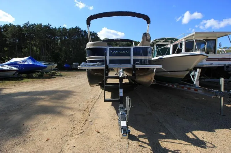 Slide: The Image of 2022 Sylvan L3 LZ pontoon boat on trailer, parked outdoors under blue sky. - 3