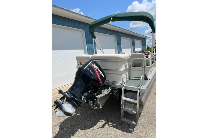 Slide: The Image of 2006 Sun Tracker Party Barge 24 with Mercury outboard motor, docked near blue building. - 10