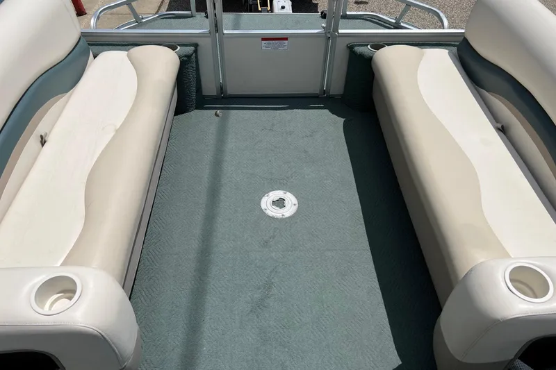 Slide: The Image of 2006 Sun Tracker Party Barge 24 interior with beige seating and green carpet. - 15