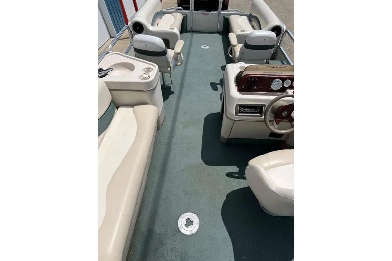 Slide: The Image of 2006 Sun Tracker Party Barge 24 interior with seating and helm, showcasing spacious layout. - 23