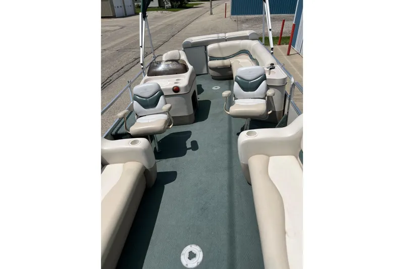 Slide: The Image of 2006 Sun Tracker Party Barge 24 interior with seating and helm, docked on a sunny day. - 25