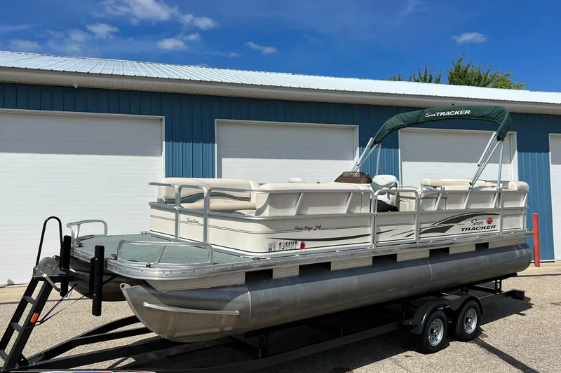 Slide: The Image of 2006 Sun Tracker Party Barge 24 pontoon boat on trailer, parked near blue building. - 8