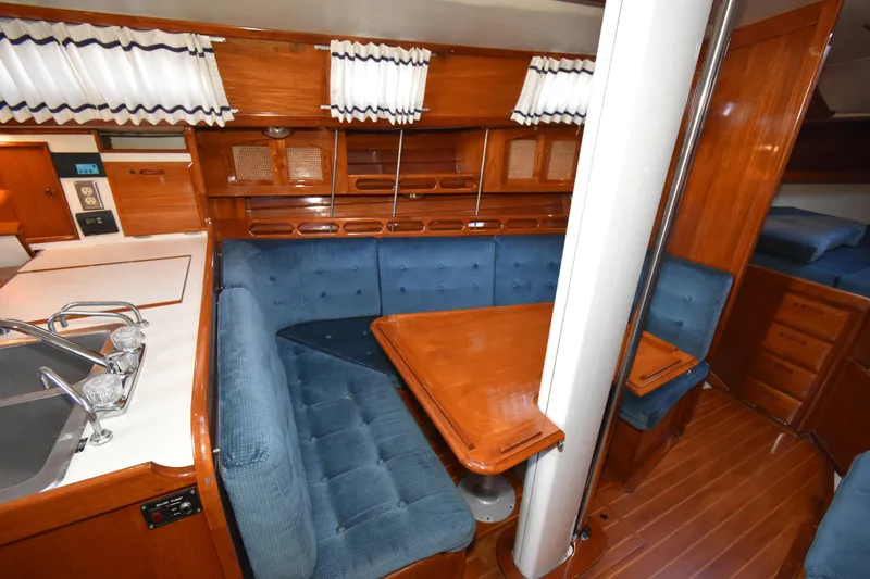 Slide: The Image of Interior of 1988 Ericson 38-200 sailboat with blue cushioned seating and wooden table. - 11