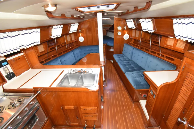 Slide: The Image of Interior of 1988 Ericson 38-200 sailboat with wood finish, blue seating, and kitchen area. - 5
