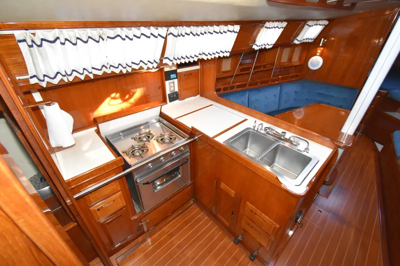 Slide: The Image of 1988 Ericson 38-200 yacht interior with wooden cabinetry, stove, sink, and dining area. - 6
