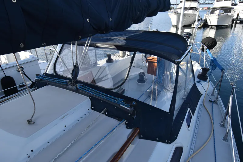 Slide: The Image of 1988 Ericson 38-200 sailboat docked, featuring a covered cockpit and marina view. - 60