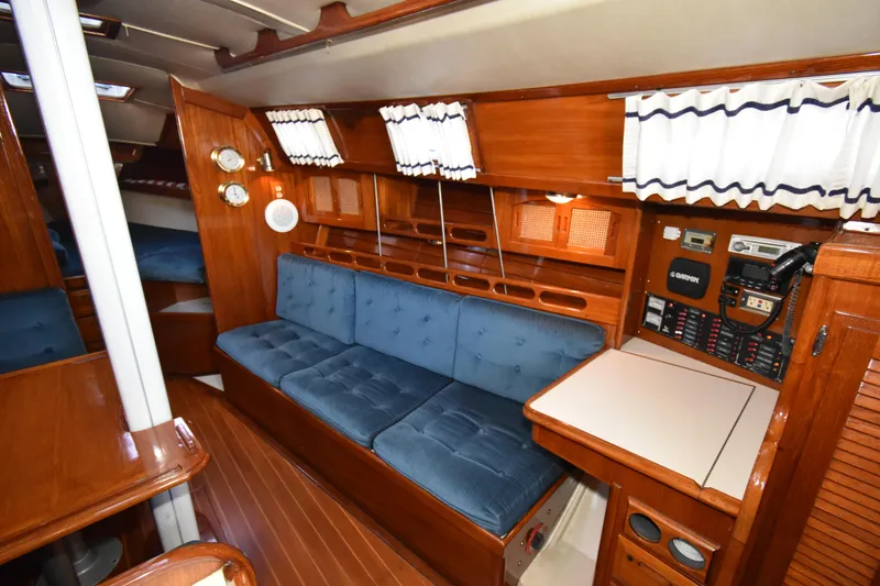 Slide: The Image of Interior of 1988 Ericson 38-200 sailboat with blue cushions, wooden finish, and navigation equipment. - 9