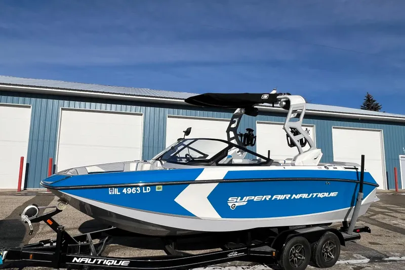 The Image of 2020 Super Air Nautique G21 boat in blue and white, parked on a trailer. - 0