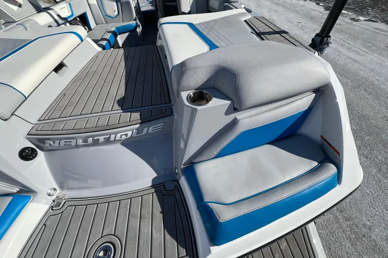 Slide: The Image of 2020 Super Air Nautique G21 boat interior with gray and blue seating and cup holder. - 10
